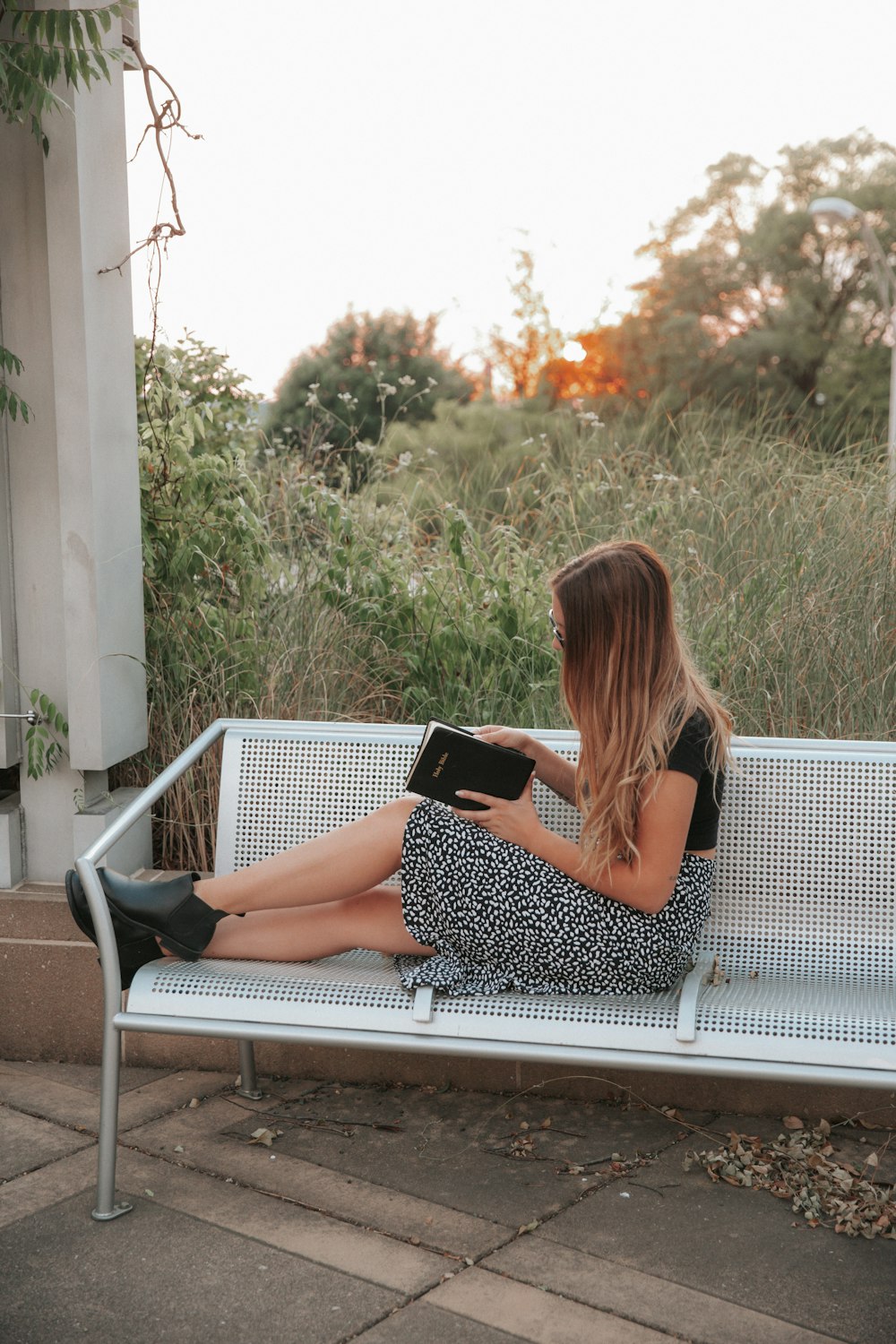 woman in black and white polka dots dress sitting on white bench during daytime