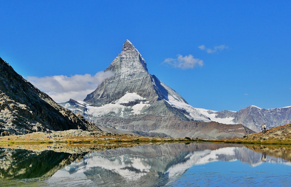 snow covered mountain near body of water during daytime