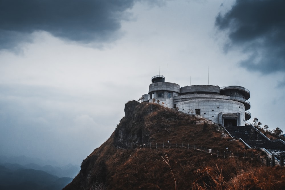 white concrete building on brown rocky mountain under white cloudy sky during daytime