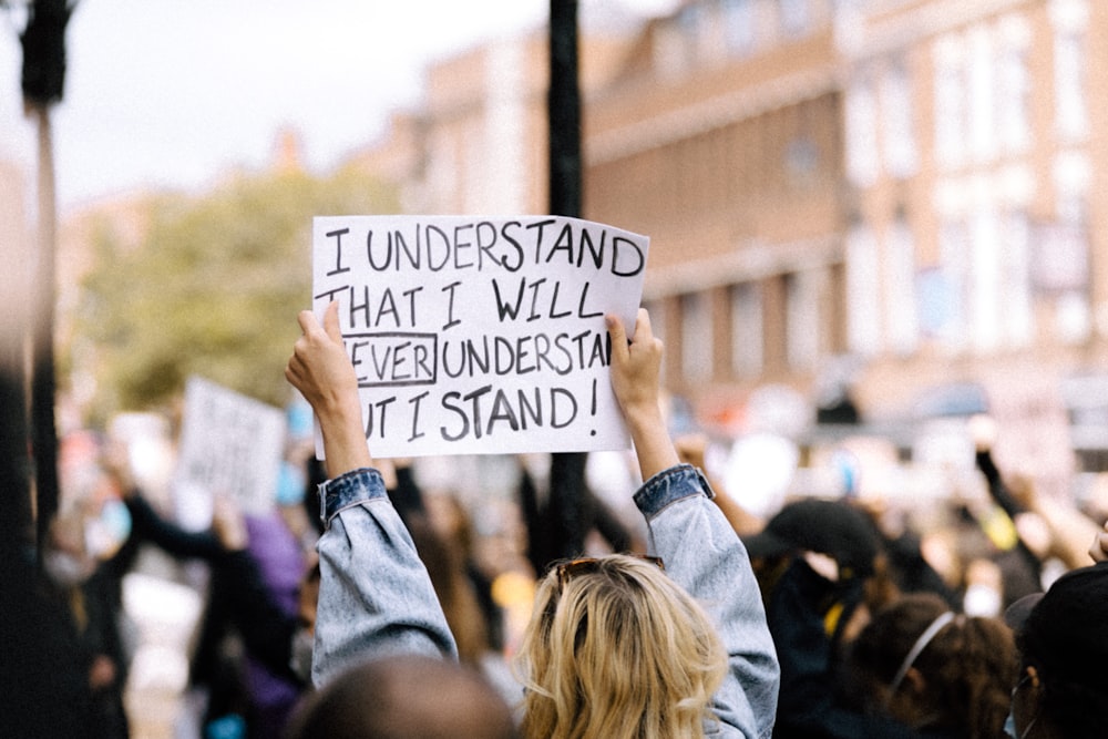 people holding white and black wooden signage during daytime