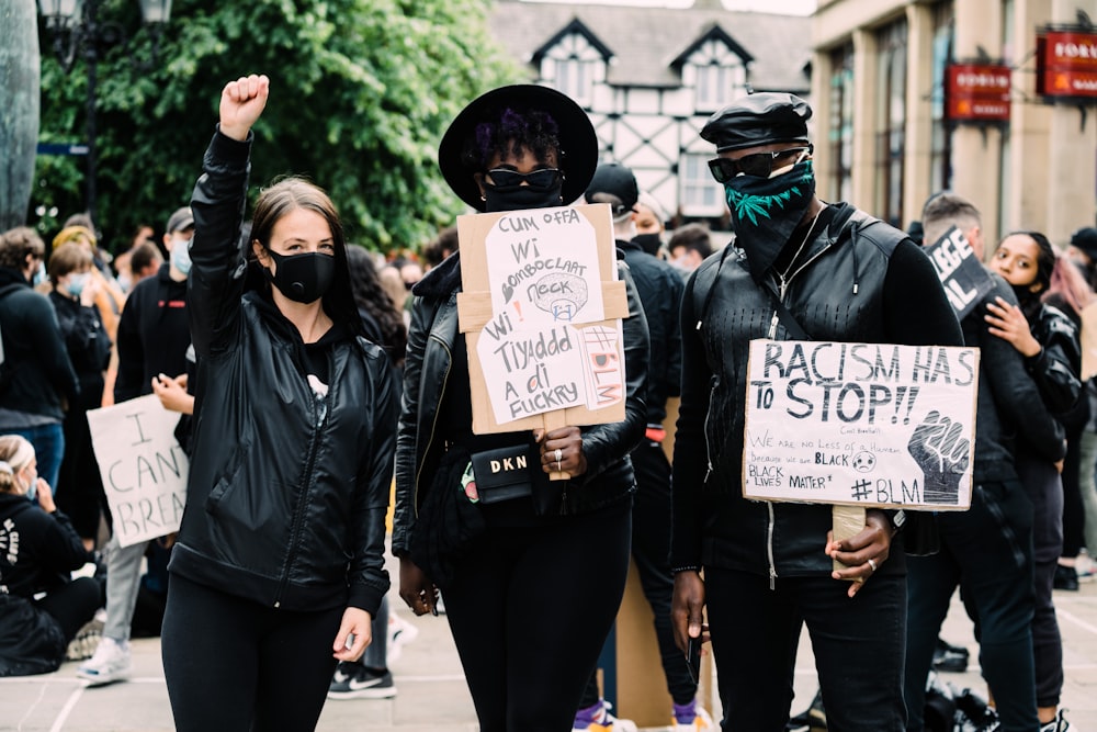 man in black leather jacket holding white and black signage