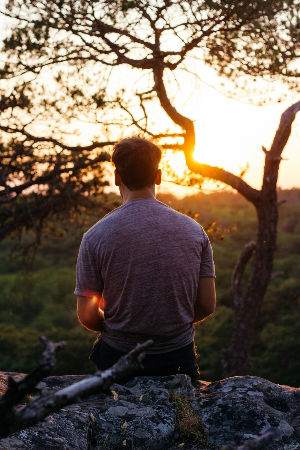 man in grey crew neck t-shirt standing near trees during daytime