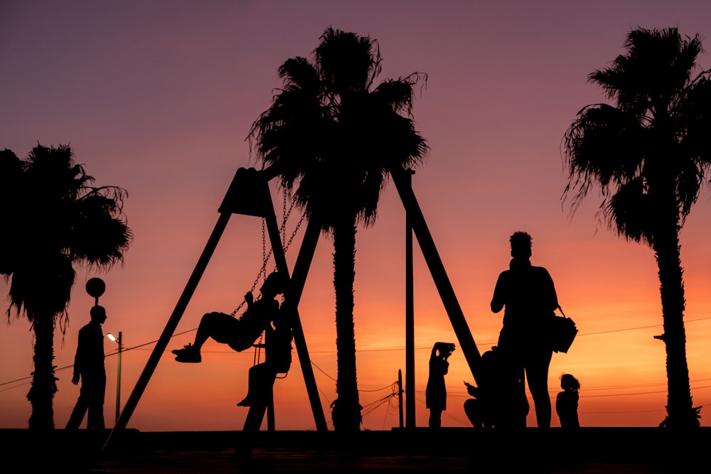 silhouette di persone sull'altalena durante il tramonto