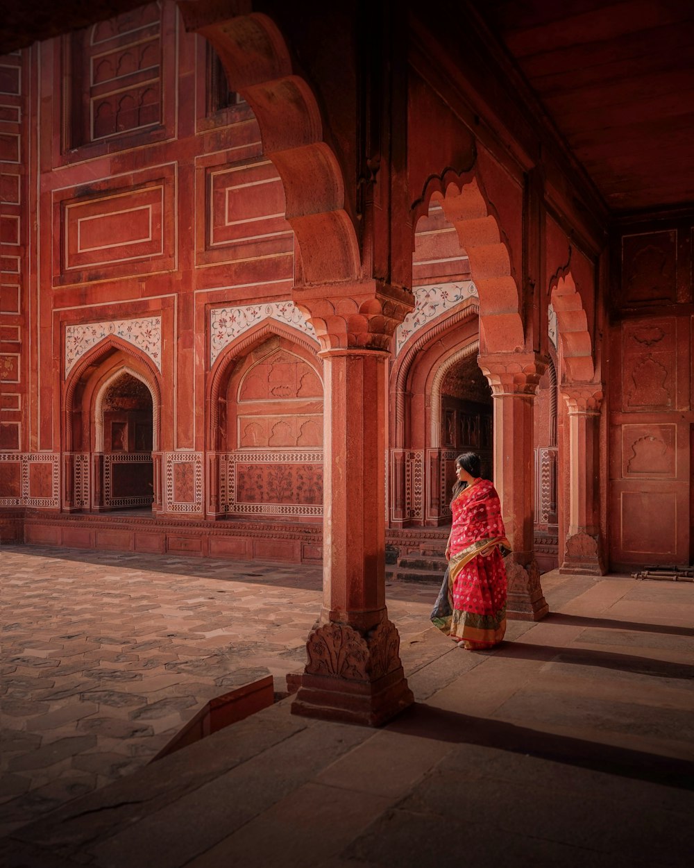 a woman in a red dress standing in a courtyard