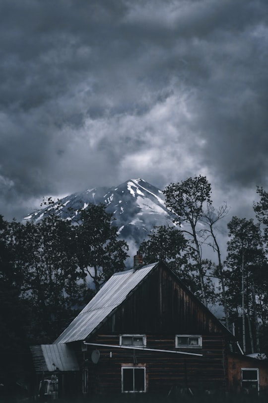 brown wooden house near green trees and snow covered mountain during daytime in Smithers Canada