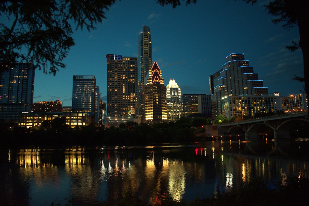 city skyline across body of water during night time