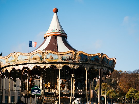 white and blue carousel under blue sky during daytime in Eiffel Tower France