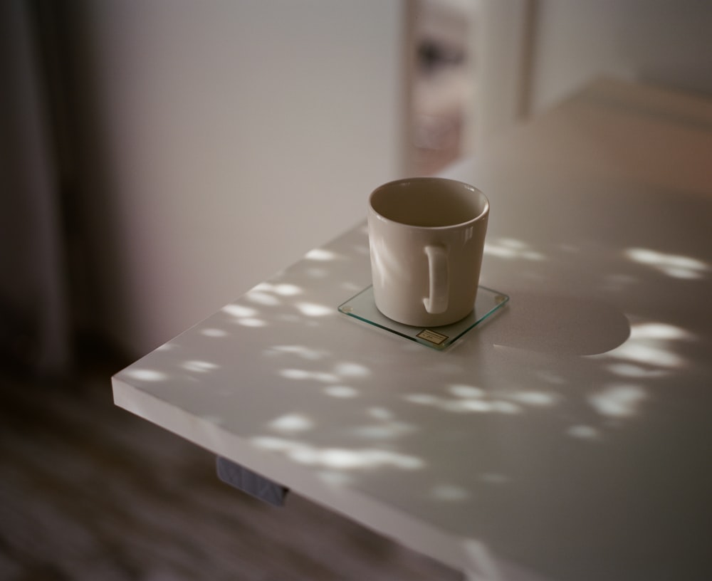 white ceramic mug on white table