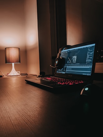black laptop computer turned on beside white desk lamp