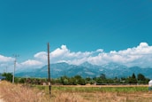 Wide shot of a rural landscape with substations and distant mountains under clear sky.