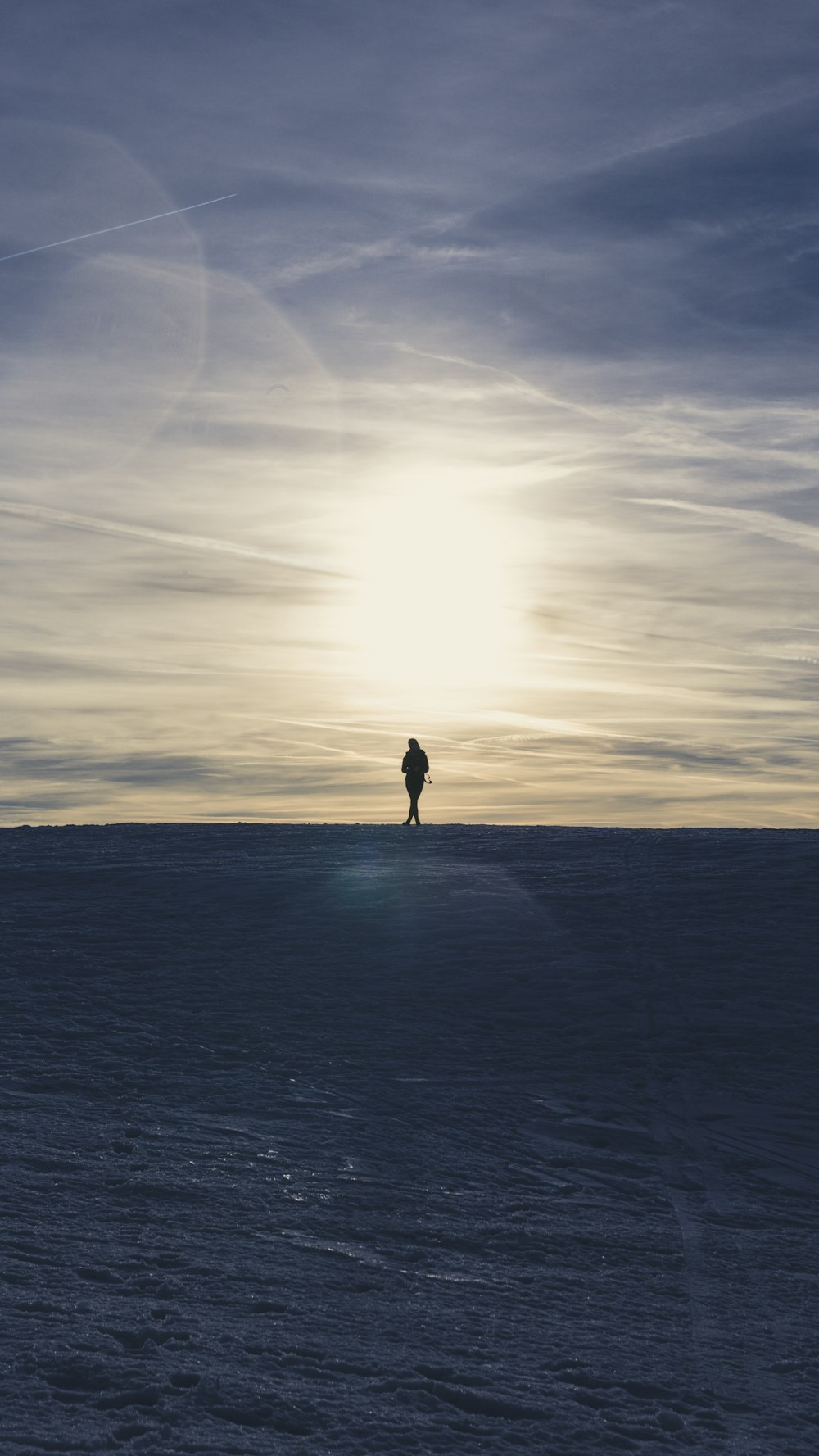 silhouette di persona che cammina sulla sabbia durante il tramonto