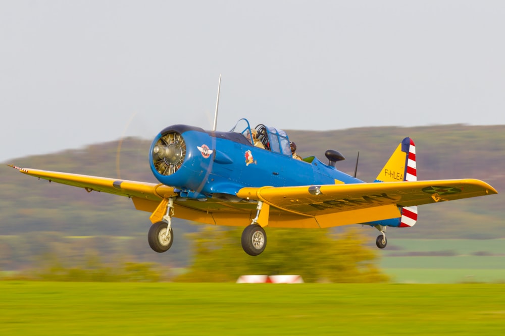 blue and yellow jet plane on brown field during daytime