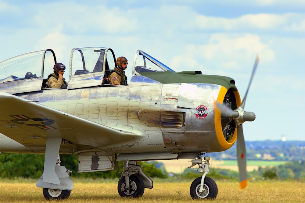 man in black jacket standing beside gray fighter plane