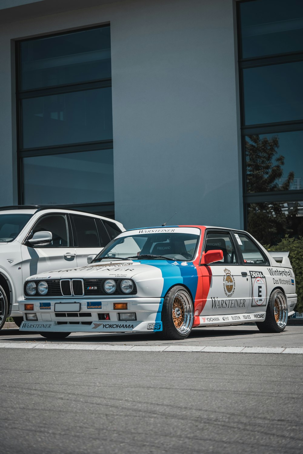white and red bmw m 3 coupe parked on gray concrete floor
