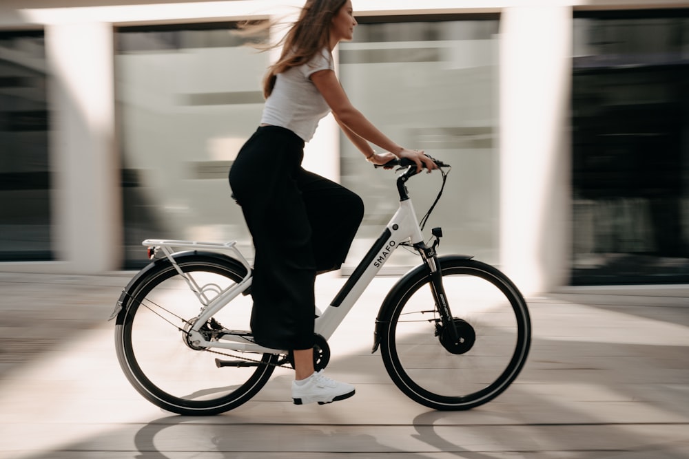 woman in white t-shirt and black pants riding on black bicycle