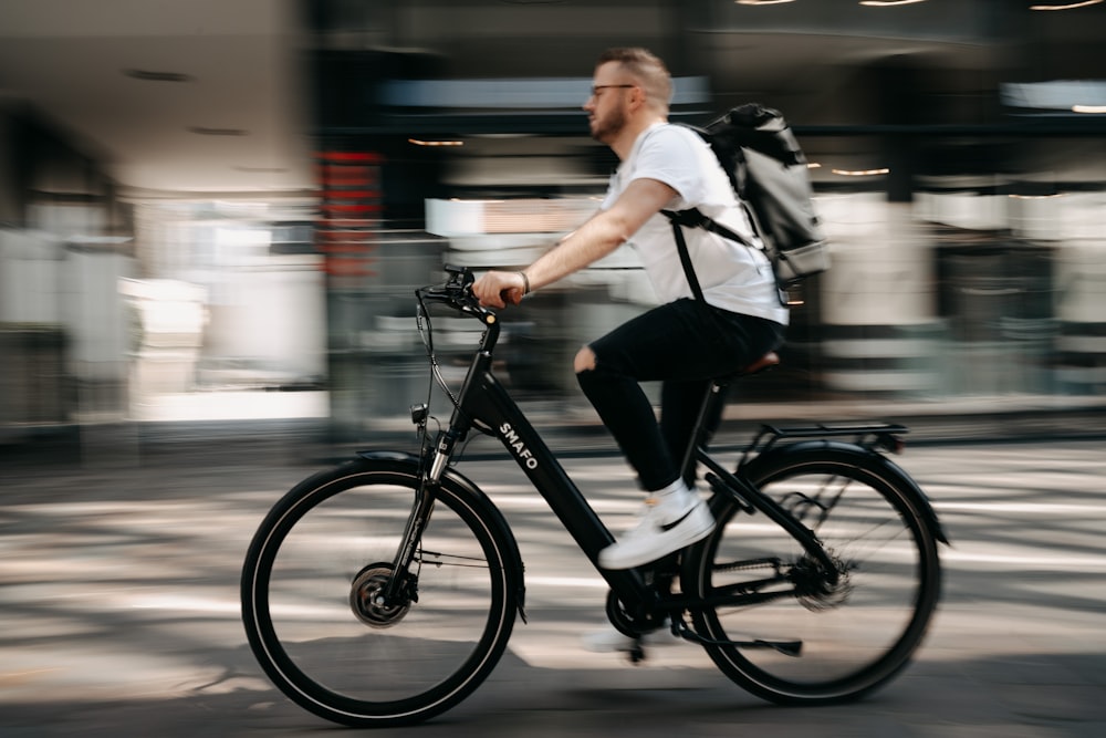 man in white dress shirt and black pants riding on bicycle