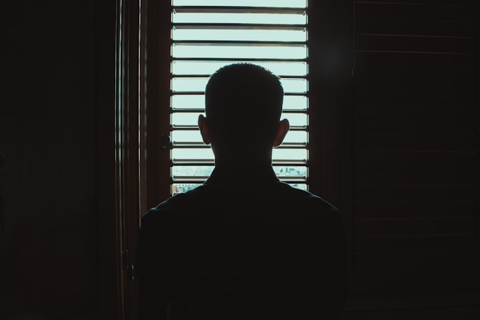 man in black crew neck shirt standing near window