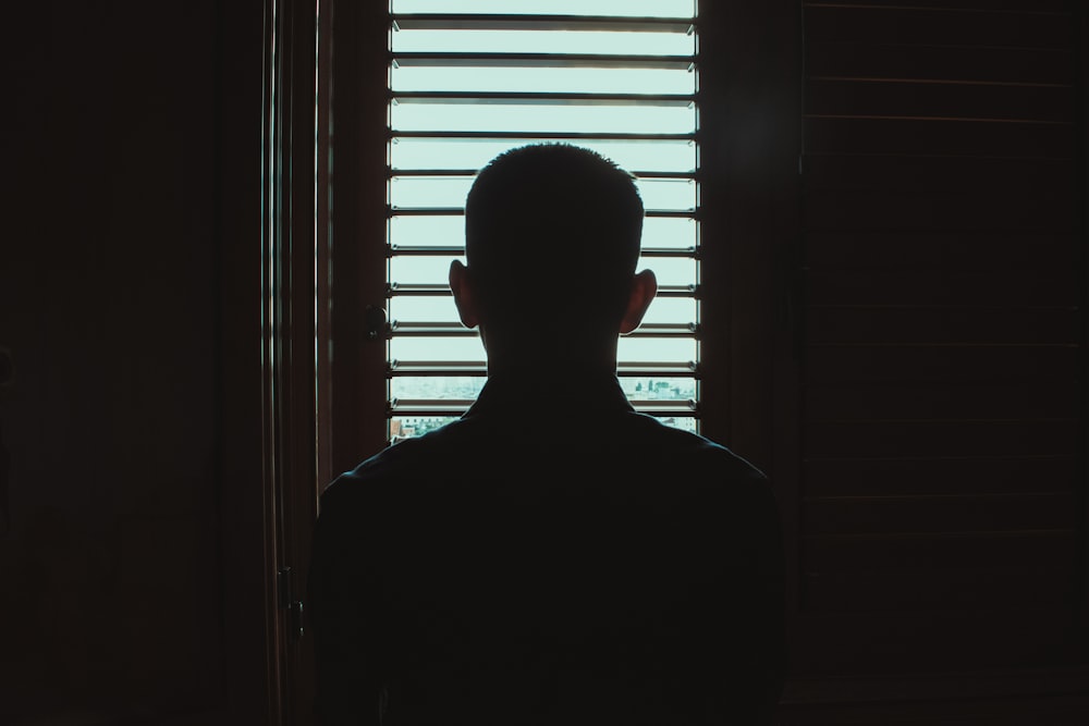 man in black crew neck shirt standing near window