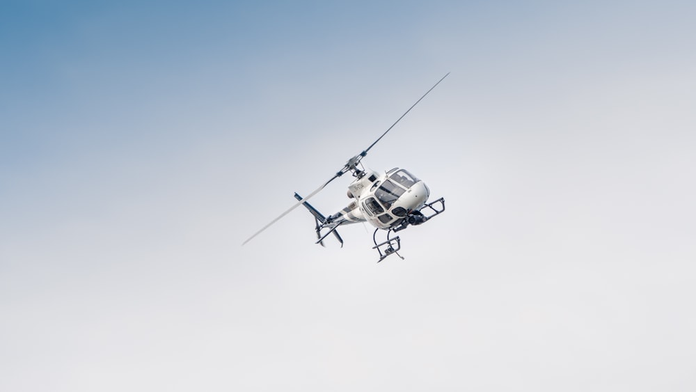 Weiße und schwarze Drohne, die tagsüber unter blauem Himmel fliegt