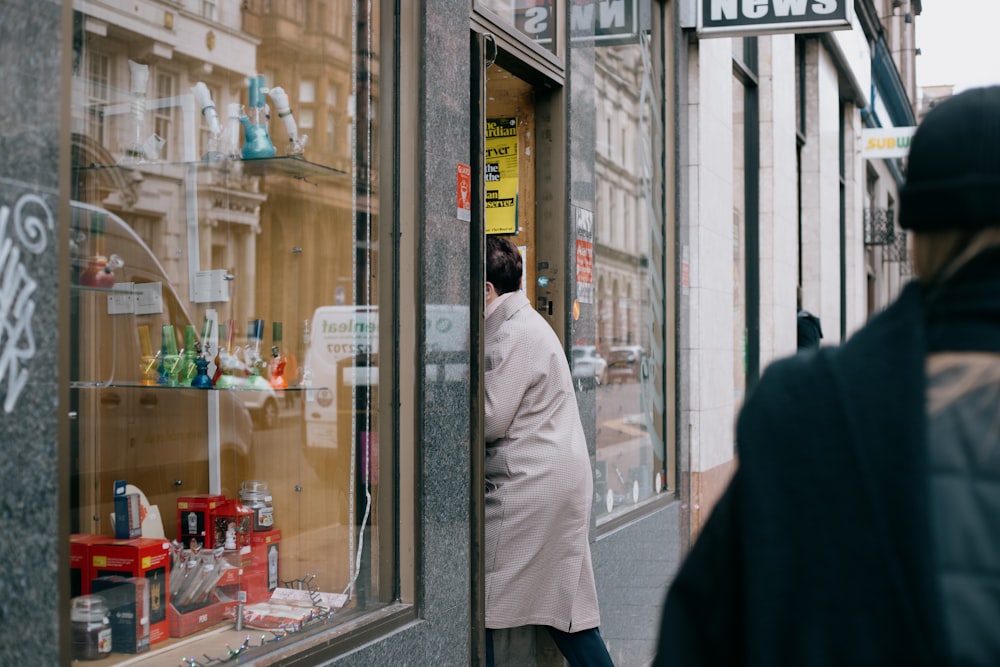 man in white dress shirt and black pants standing near glass window