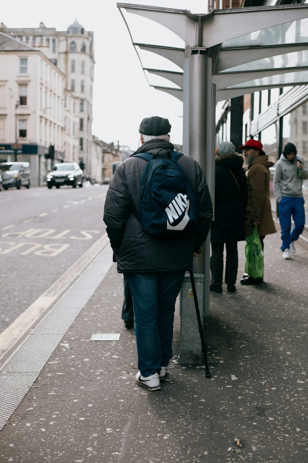 man in black jacket and gray pants walking on sidewalk during daytime
