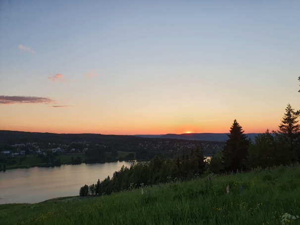 A peaceful landscape with a sunset over a tranquil lake.