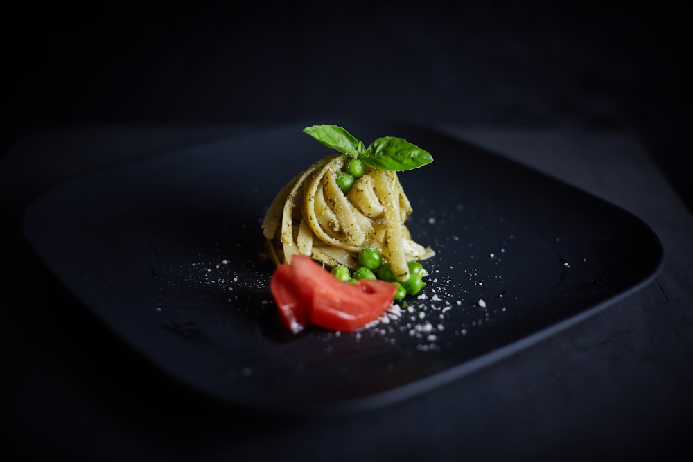sliced tomato and green vegetable on black plate