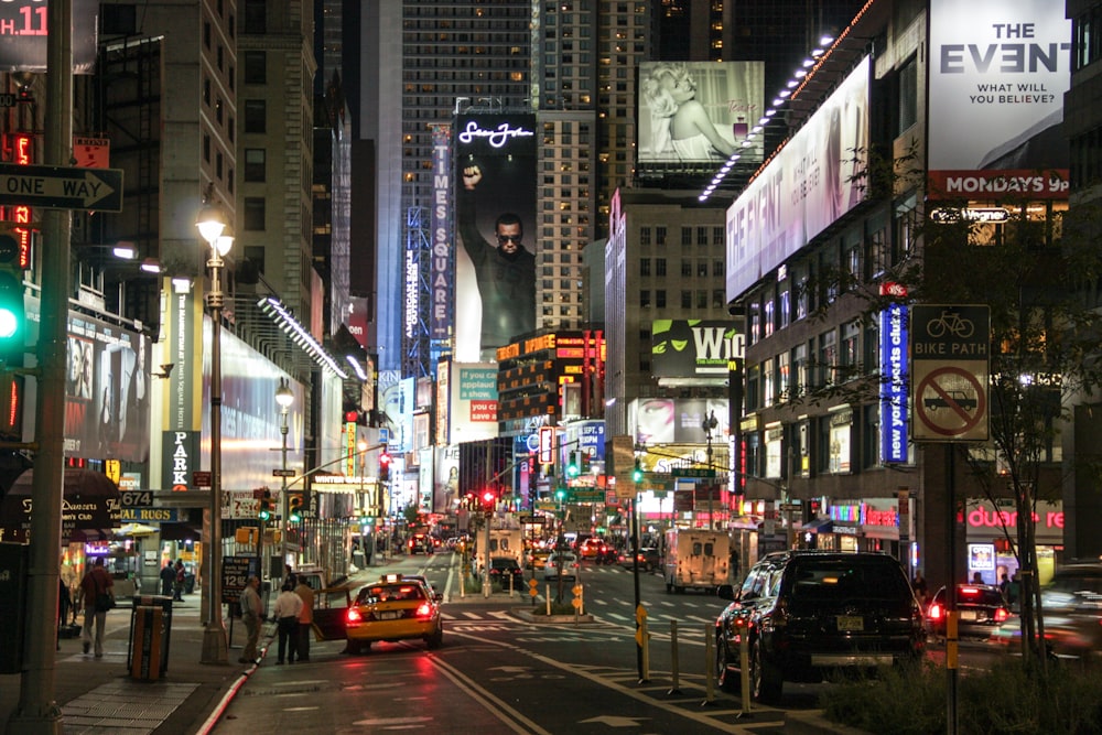 cars on road between high rise buildings during night time