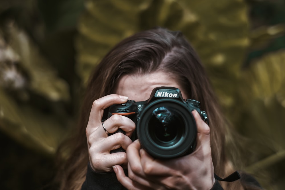 woman holding black nikon dslr camera