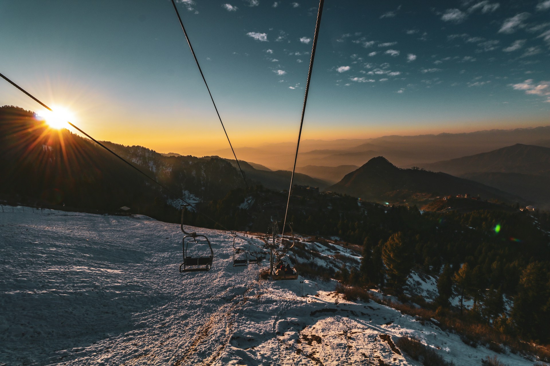 A person riding a ski lift at sunset