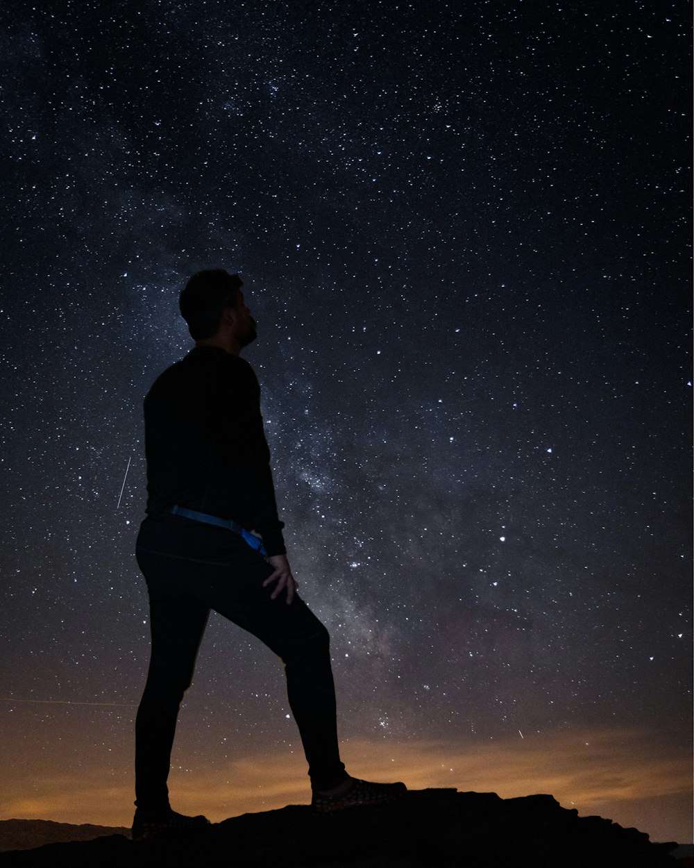 man in black shirt and blue pants standing under starry night