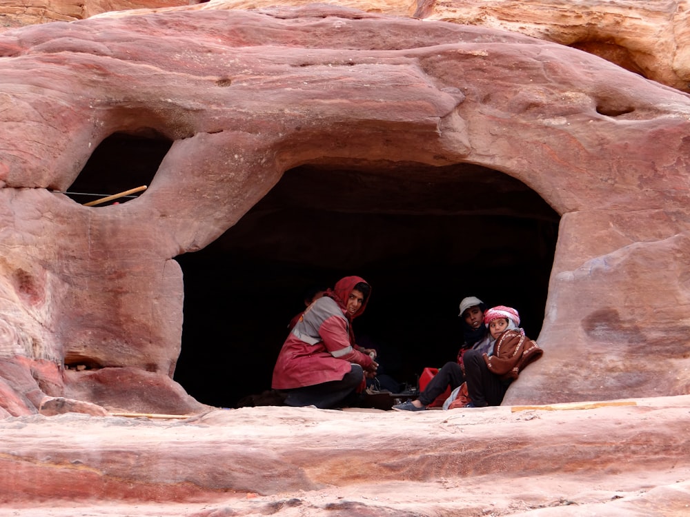 2 boys sitting on rock formation during daytime