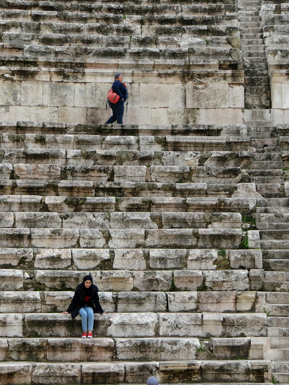 man in blue jacket walking on gray concrete stairs