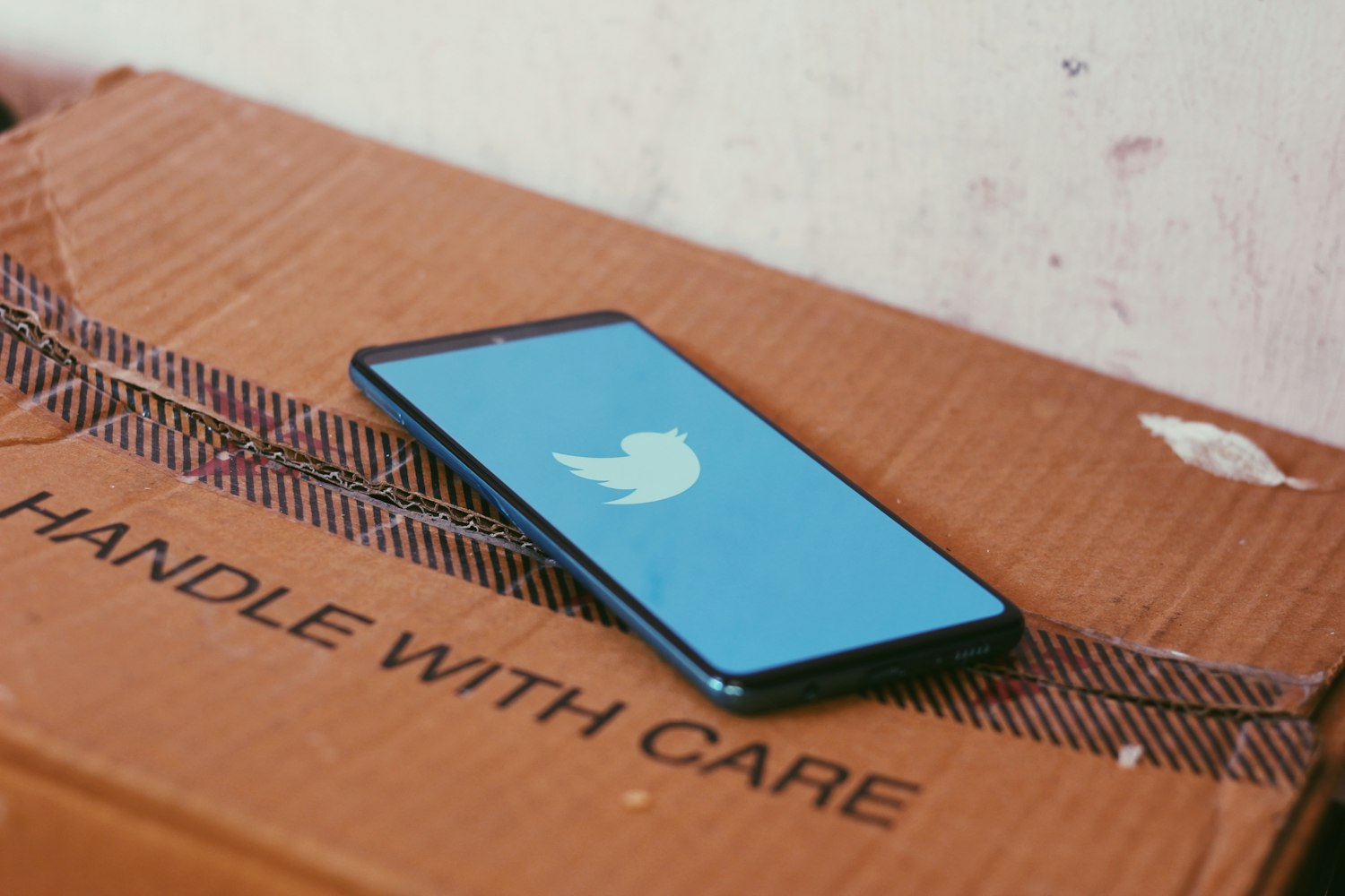 Phone showing Twitter label on a box saying 'Handle with Care'