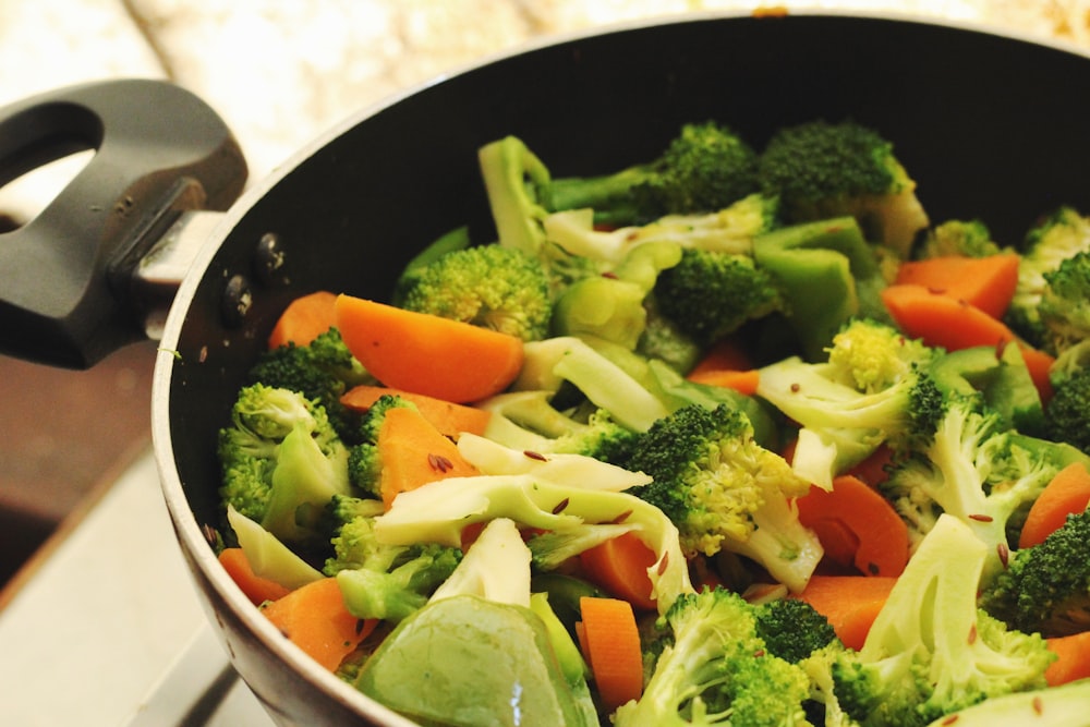 Ensalada de verduras verdes y naranjas en bol de cerámica blanca