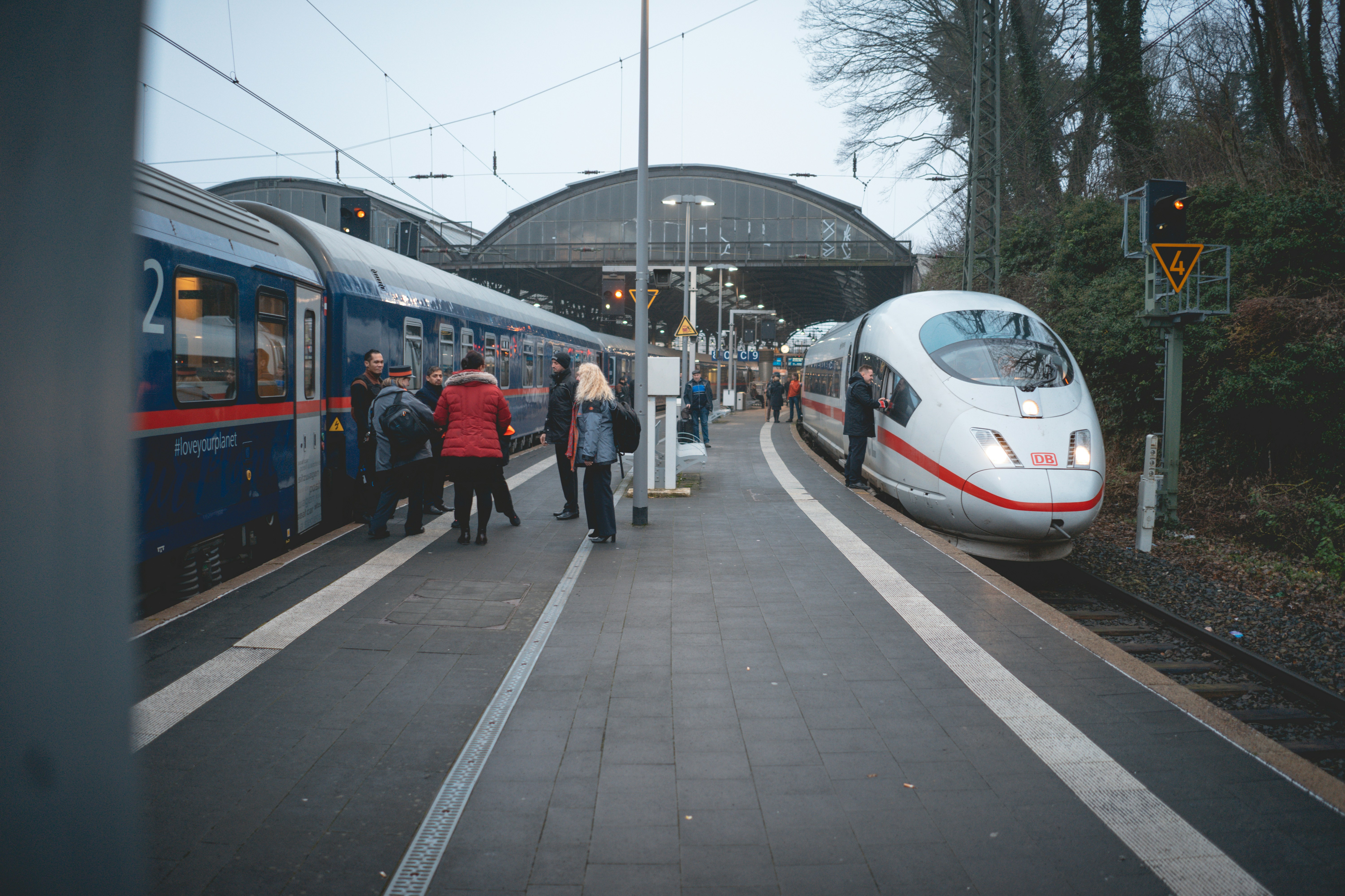 Menschen, die tagsüber auf dem Bürgersteig in der Nähe des weißen und blauen Zuges spazieren gehen