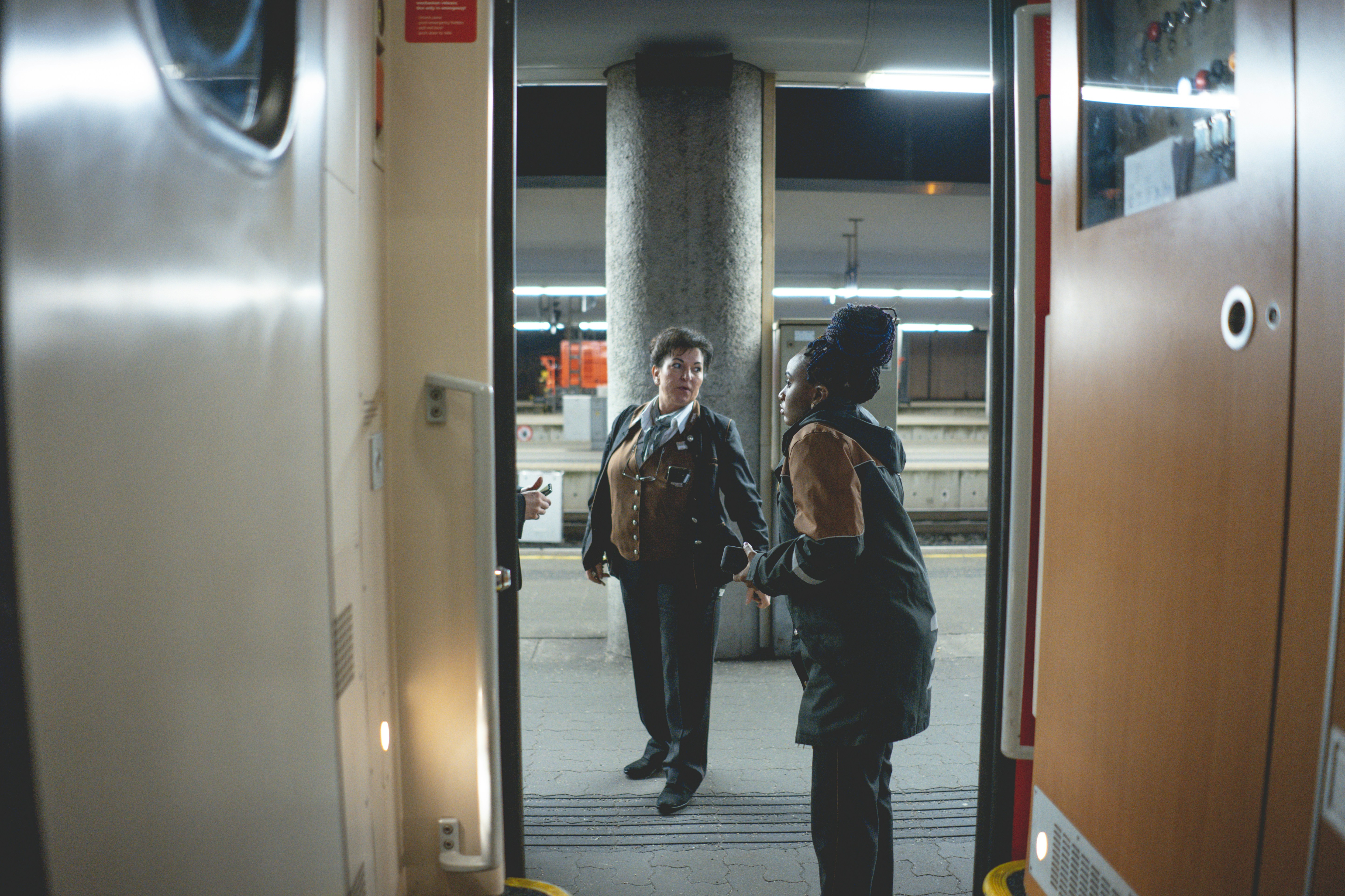 Mann in schwarzer Jacke und schwarzer Hose neben weißer Wand