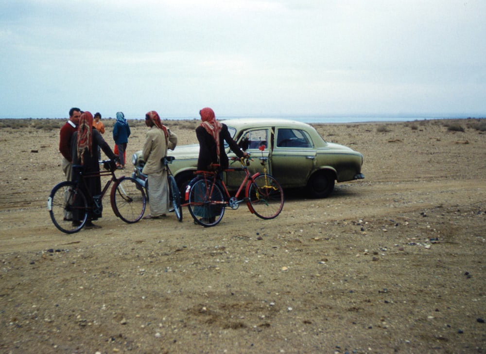 people standing beside blue and black bicycle during daytime