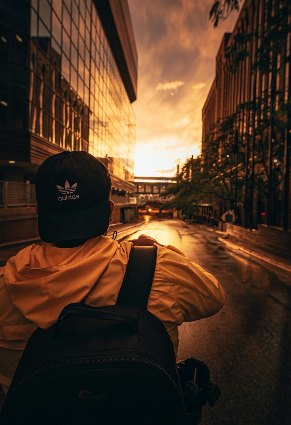 man in black cap and brown jacket standing on sidewalk during daytime