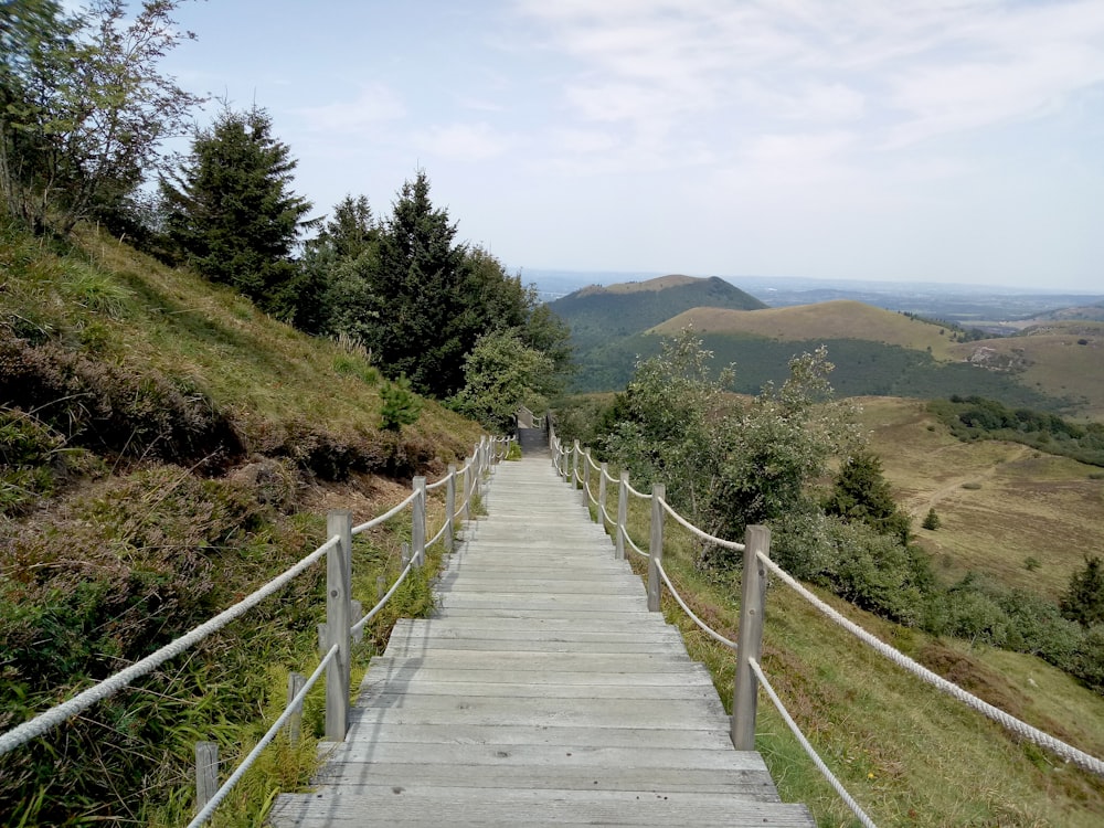 brown wooden bridge over green mountains during daytime