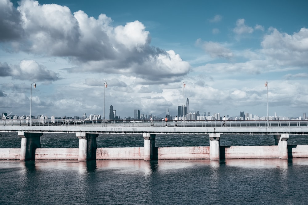 gray concrete bridge under white clouds and blue sky during daytime