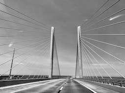 grayscale photo of bridge under cloudy sky