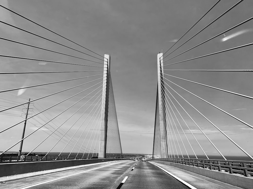 grayscale photo of bridge under cloudy sky