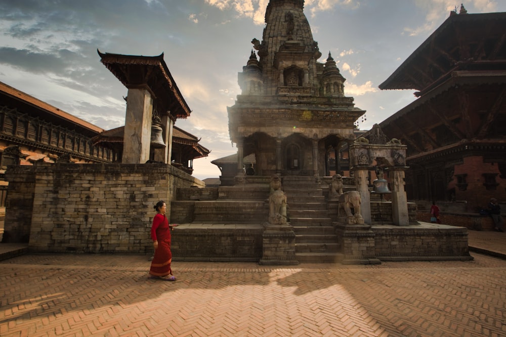 woman in red dress standing near temple during daytime