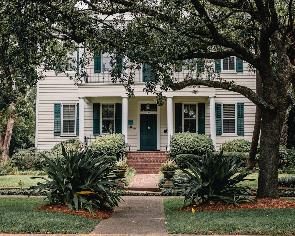 white wooden house near green trees during daytime