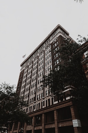 A stately, historic building with classic brickwork and an American flag waving gently in front.