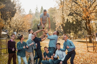 A group of students using leaf blowers in a residential yard during autumn.