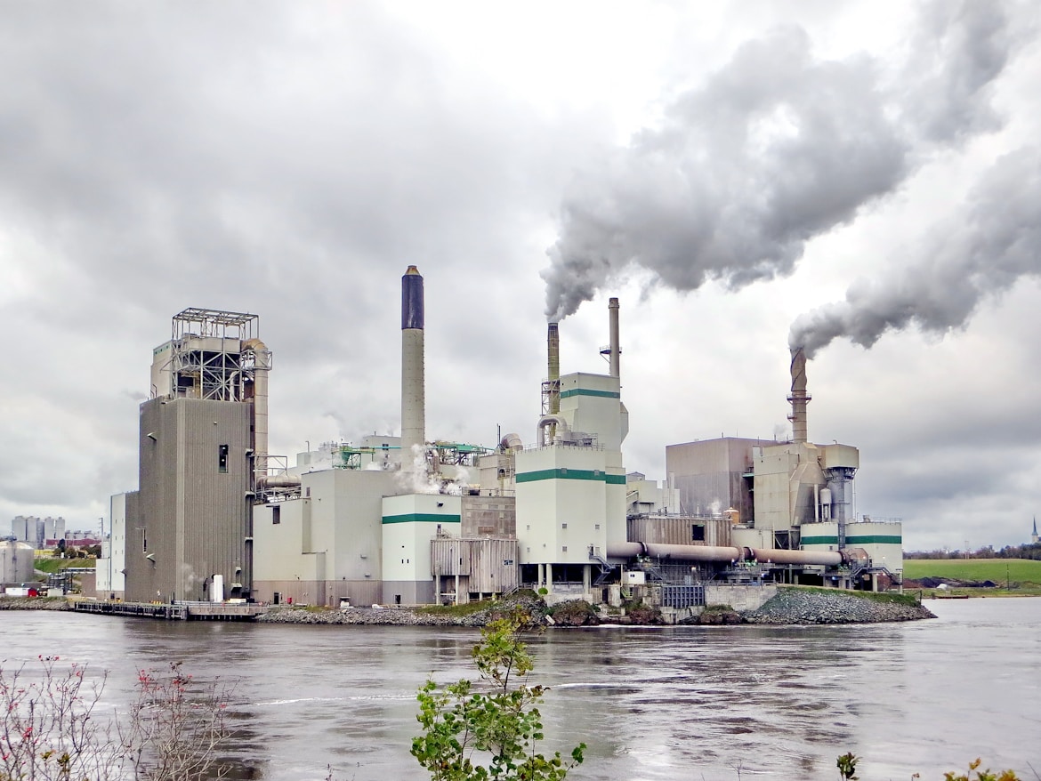 white and green factory building near body of water during daytime