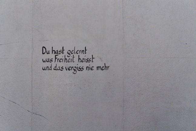 A light gray wall features text written in black, stylized handwriting. The words are in German and read, 'Du hast gelernt was Freiheit heisst und das vergiss nie mehr.'