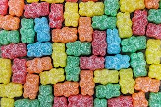 Colorful trays of gummies arranged in neat rows on a factory table.